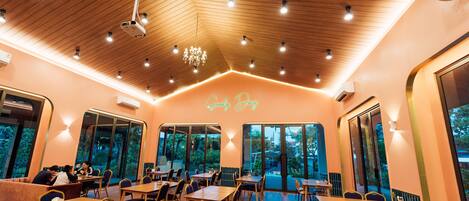 A restaurant with wooden ceiling, tables, chairs, and a neon sign reading "Good Day".