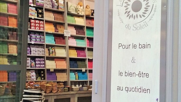 A storefront with shelves stocked with colorful packaged goods, a stack of books, and a sign advertising 'Savonneries Artisanales de Marseille'. - 5mn from Uzes, air-conditioned gîte in the heart of the vineyards (Blauzac)