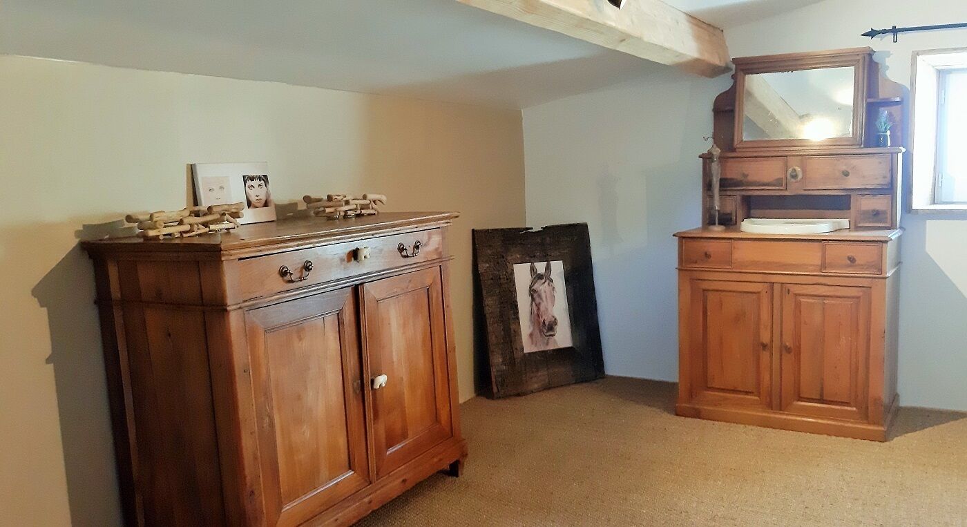 A room with a wooden dresser, a mirror, and a framed picture on the wall.