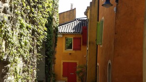 Un stretto vicolo acciottolato con una porta rossa e una campana a destra.