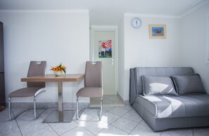 A modern living room with a grey sofa, two chairs, a wooden table, and a vase of flowers.