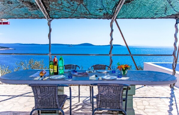 An outdoor dining area with a table set for two, overlooking a scenic view of the sea.