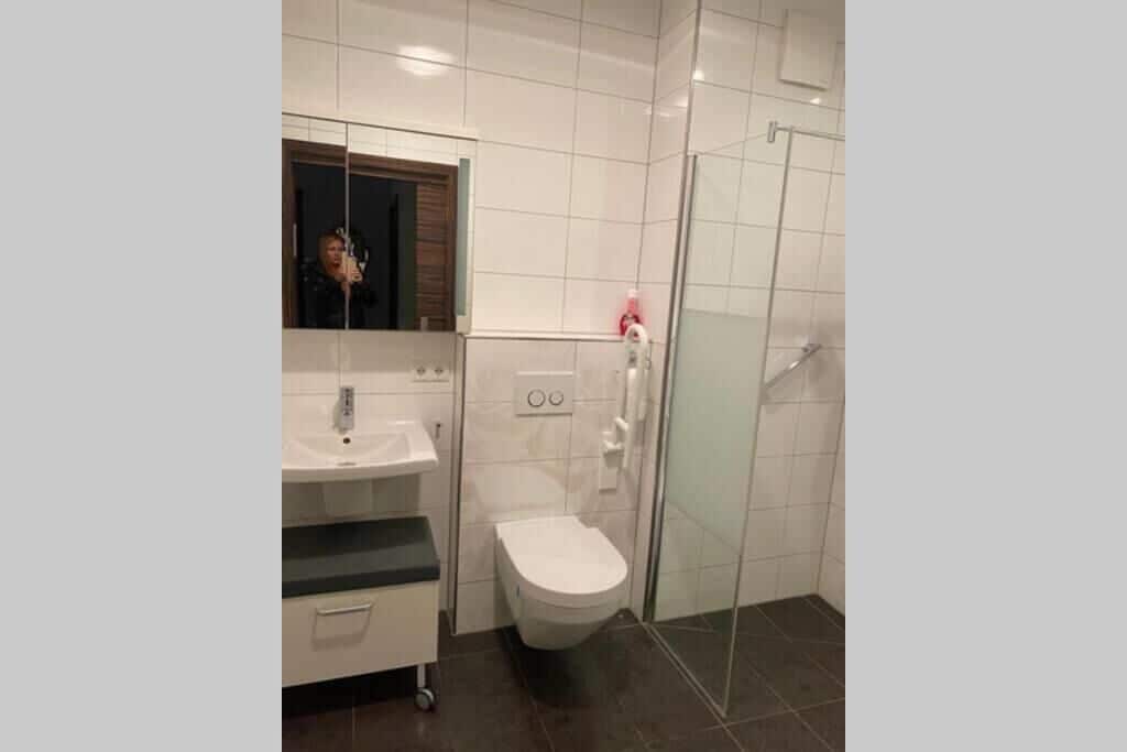 A modern bathroom with a white sink, toilet, and glass shower enclosure.