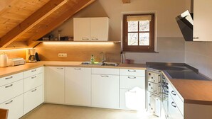 Cozinha moderna com armários brancos, teto de madeira e janela com vista.