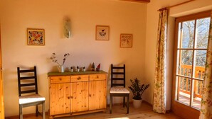 Um quarto acolhedor com piso de madeira, um armário de madeira, duas cadeiras e uma janela com cortinas.