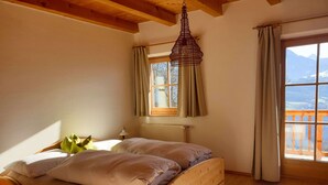 Uma cama de madeira em um quarto com janela, cortinas e um lustre.