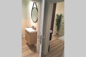 A modern bathroom with a wooden floor, a white sink, a mirror, and a potted plant. - Luxury Large 4 Beds, 3 Balconies, 110 m2 - Parking (Luxembourg City)