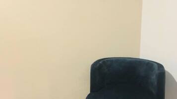 Une pièce comprenant un fauteuil recouvert d’un tissu turquoise, un petit panier turquoise et trois miroirs ovales accrochés au mur.