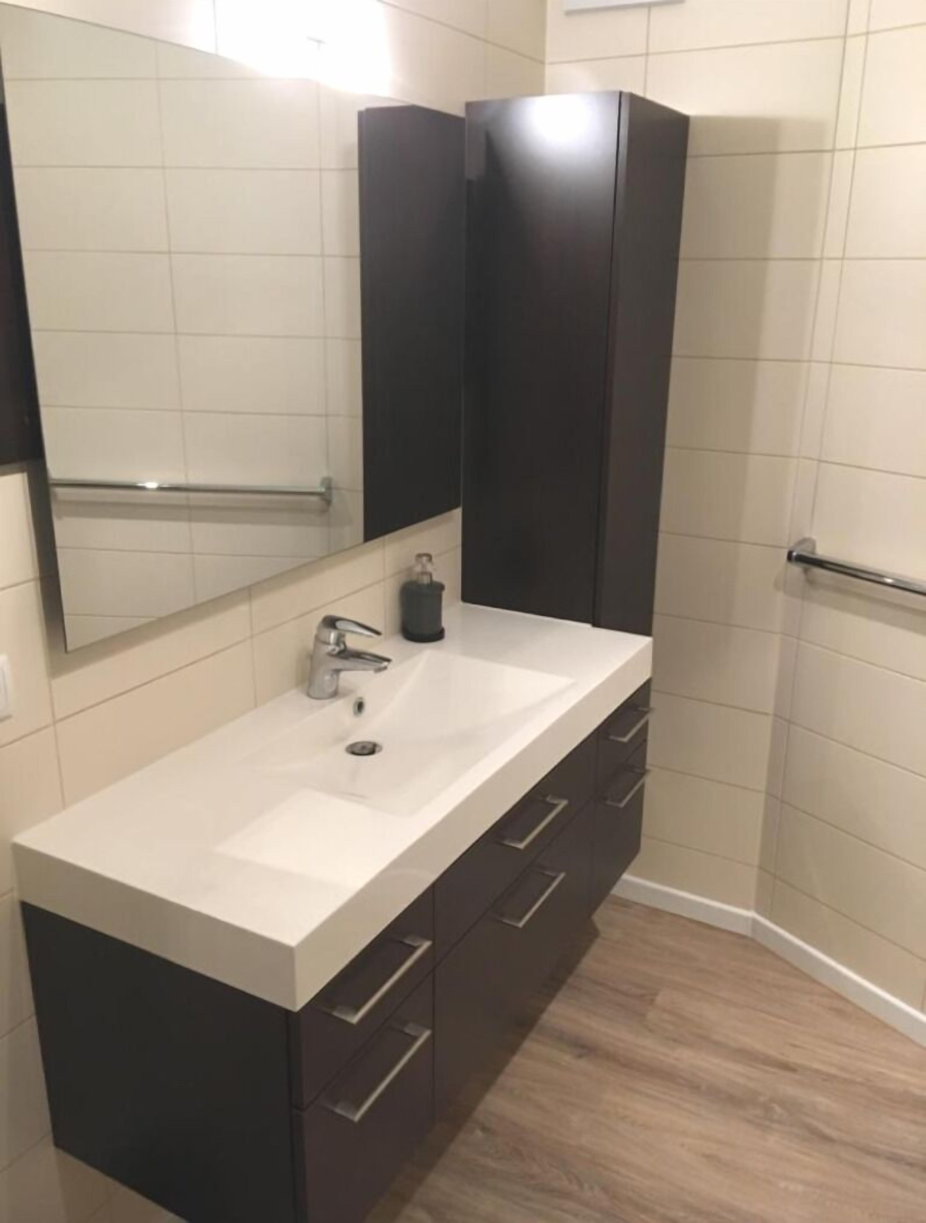 A modern bathroom with a white sink, dark cabinets, and a mirror above the sink.