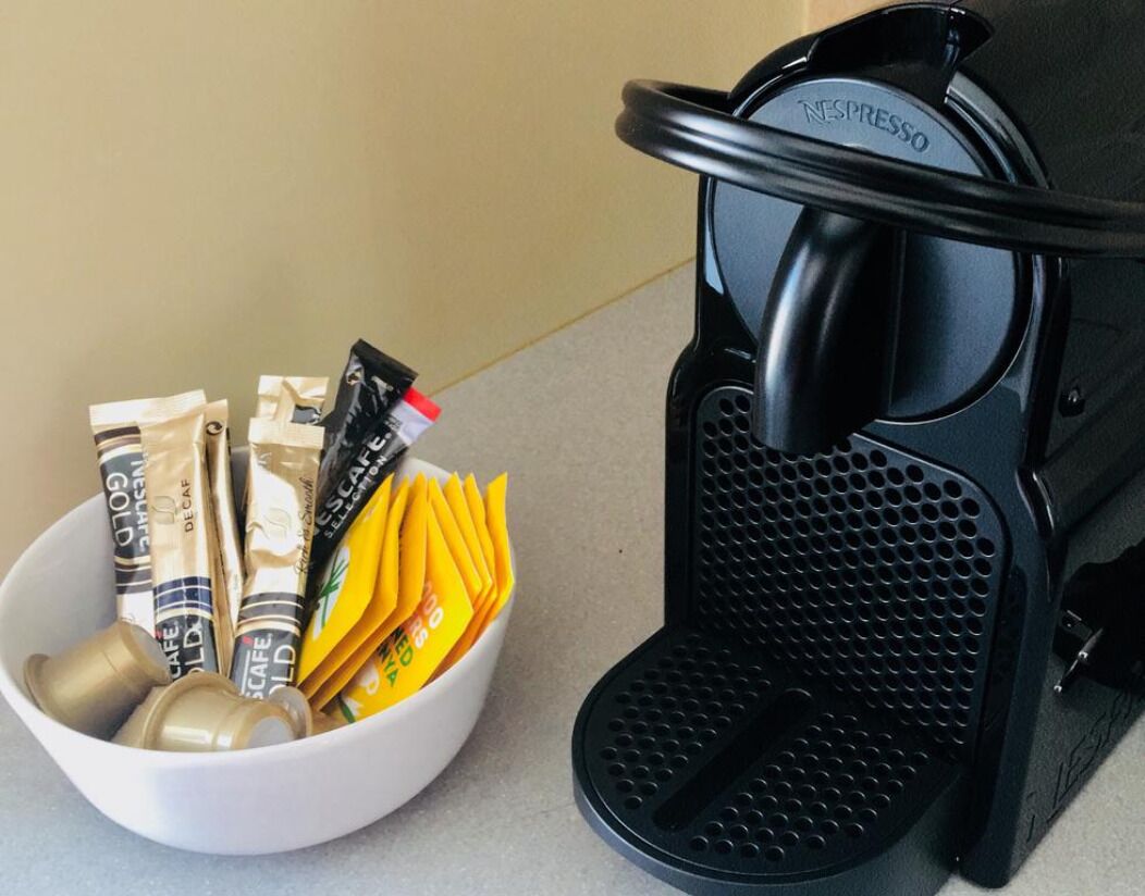 A Nespresso coffee machine with a bowl of coffee capsules and a cup of coffee.