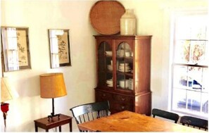 A dining area with a wooden table, chairs, a cabinet with glass doors, and wall-mounted artwork.