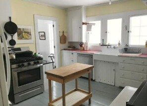 A compact kitchen with a stove, oven, and a wooden table.