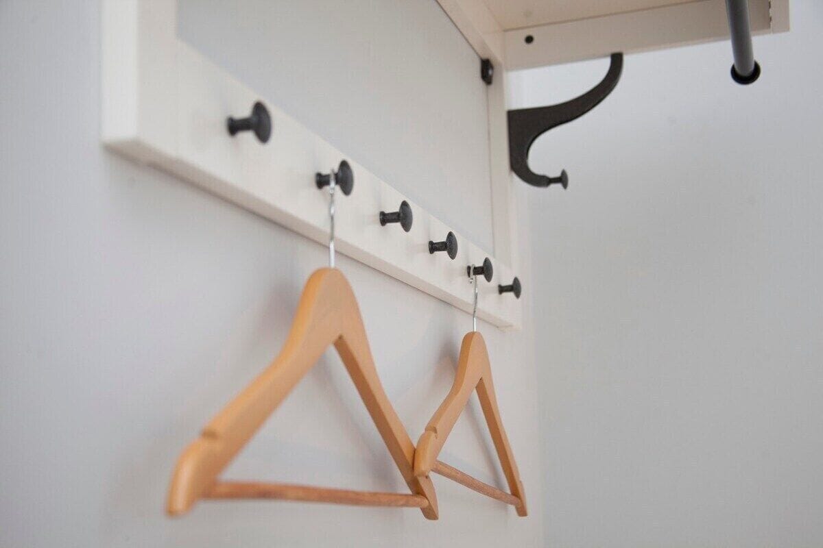 A coat rack with multiple hooks and a wooden hanger.
