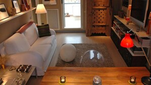 A modern living room with a white sofa, a wooden coffee table, and a TV on a wooden stand. - Luxury 10thfloor Penthouse Stunning View Over Rome. Big Terrace (Roma)