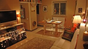 A living room with a TV, speakers, and a dining table set for two. - Luxury 10thfloor Penthouse Stunning View Over Rome. Big Terrace (Roma)