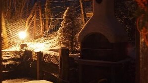 A snow-covered outdoor area with a wooden bench and a stone structure, possibly a fireplace or oven, under a wooden archway. - An Authentic Chalet near the cable car in Saint-gervais-les-bains (Saint-Gervais-Les-Bains)