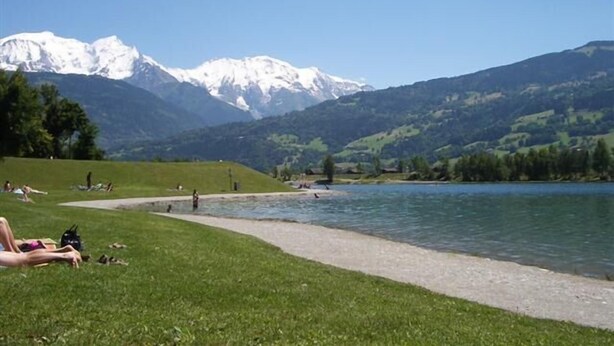 A lakeside view with a path leading to the water, surrounded by green hills and snow-capped mountains in the background. - An Authentic Chalet near the cable car in Saint-gervais-les-bains (Saint-Gervais-Les-Bains)