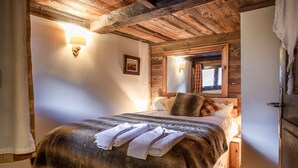 A cozy bedroom with a wooden ceiling, a bed with a fluffy blanket, pillows, and a bedside table with a lamp. - An Authentic Chalet near the cable car in Saint-gervais-les-bains (Saint-Gervais-Les-Bains)