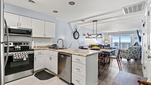 A modern kitchen with white cabinets, stainless steel appliances, and a large island.