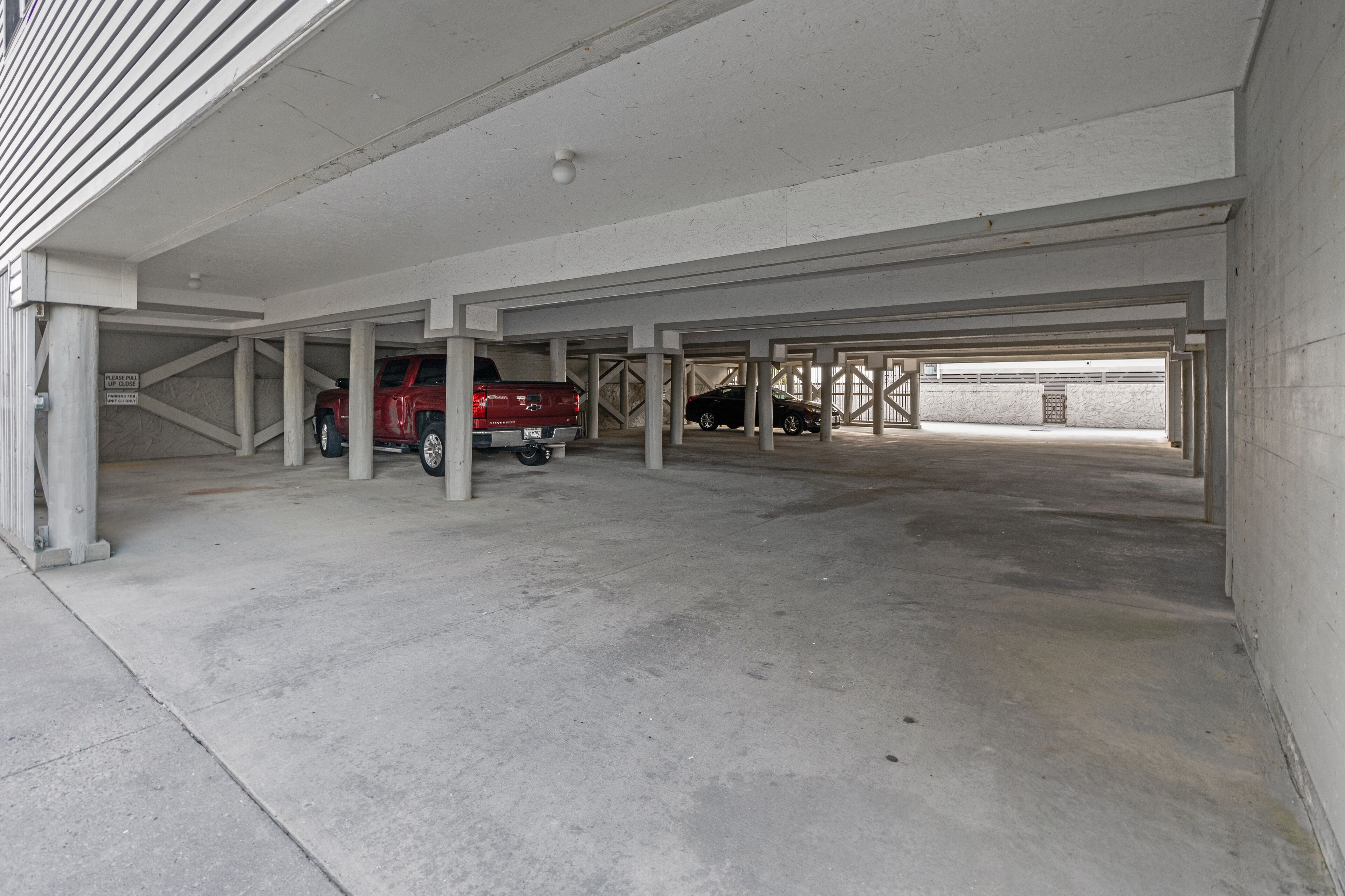Een parkeergarage met betonnen pilaren en een rode vrachtwagen.