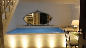 Une petite salle de bain intime, dotée d’une baignoire, d’un miroir et d’une chaise.