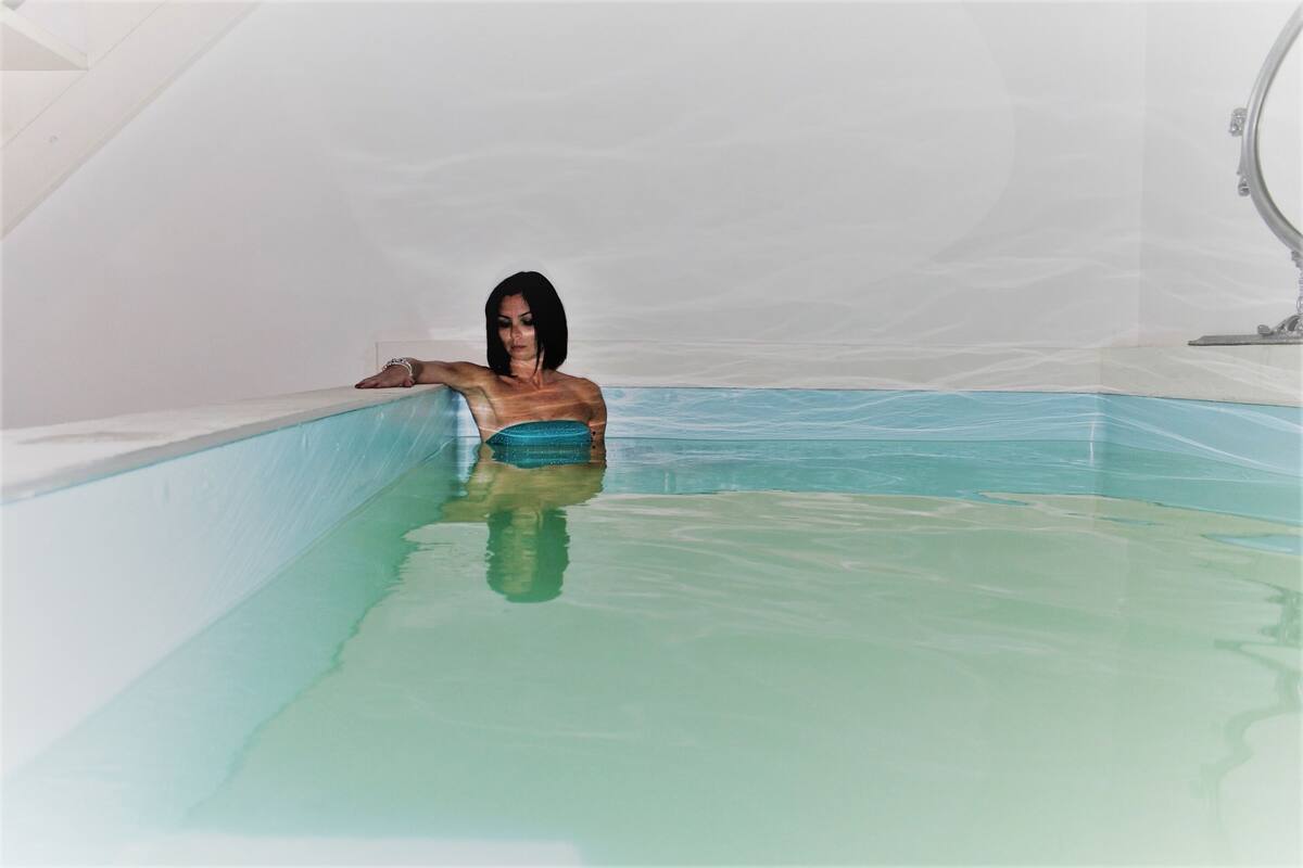 Une personne dans une baignoire dont l’intérieur est blanc et l’eau est légèrement bleutée.