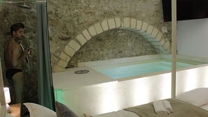 Une pièce avec un mur en pierre, une baignoire et un lit avec des serviettes.
