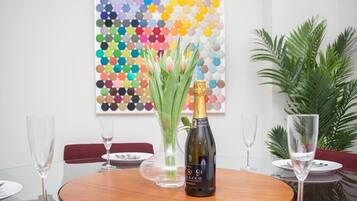 Ein runder Holztisch mit einer Champagnerflasche, einem Blumenstrauß und leeren Weingläsern.