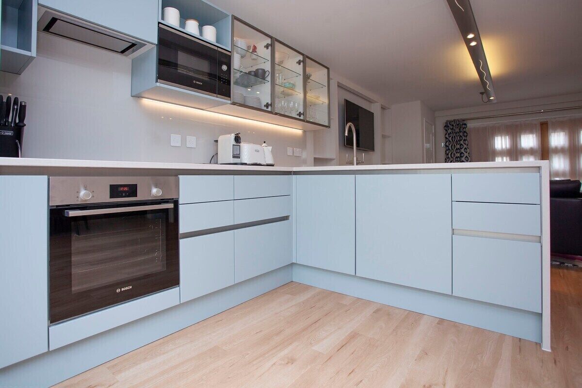 Une cuisine moderne avec des meubles blancs, un four Bosch et un micro-ondes encastré.