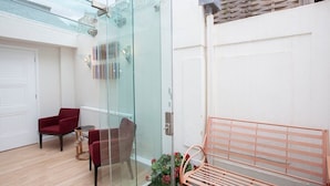 Un intérieur moderne avec une cloison en verre, un banc en bois et deux chaises rouges.