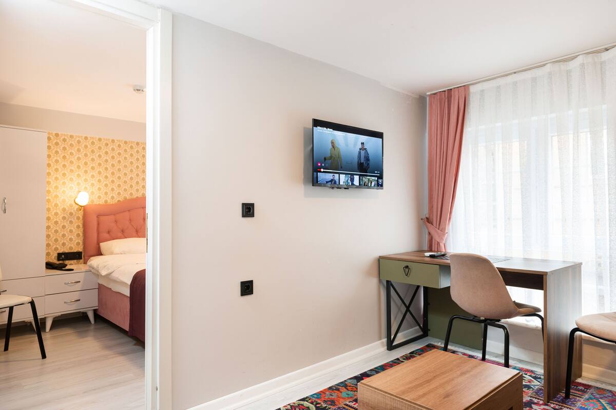 Una habitación de hotel moderna con cama, escritorio, silla y televisor montado en la pared.