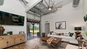 A spacious living room with a large flat-screen TV, a wooden coffee table, a white sofa, and a cowhide rug. - The Bonnie (Bulverde)