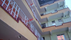 A multi-story building with balconies, each with white railings and a red base. - Hotel Daddy's (Thika)