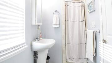 Ein Badezimmer mit einem weißen Waschbecken, einem Spiegel, einer Duschvorhang und einem weißen Handtuch an der Wand.