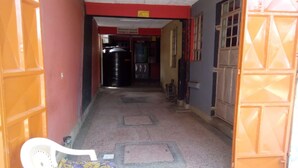 A hallway with a bench, a trash bin, and a door leading to a room. - Ruby G Hotel and Club (Ruiru)