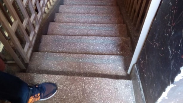 A staircase with metal railings and a patterned floor leading to a door with a black marble finish. - Ruby G Hotel and Club (Ruiru)