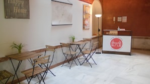 A reception area with a wooden bench, a map on the wall, and a sign for San Isidoro Hostel Sevilla. - San Isidoro Hostel Sevilla (Seville)