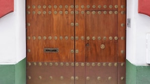 A wooden double door with metal studs, a number '30' above it, and a small metal plate on the left door. - San Isidoro Hostel Sevilla (Seville)