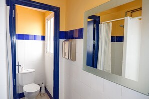 A bathroom with a toilet, a sink, and a shower area. - San Isidoro Hostel Sevilla (Seville)