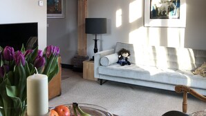 Un salón acogedor con techo de madera, un sofá, una lámpara y un cuadro en la pared.