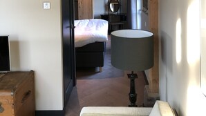 Un dormitorio con cama, cómoda, espejo y lámpara.