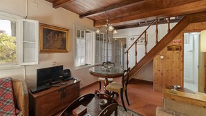 A cozy living room with a wooden ceiling, a dining table with chairs, a television, and a painting on the wall. - Quinta Florença - By Wehost (Funchal)