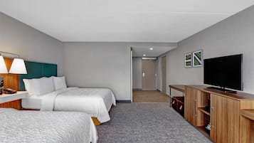 Habitación de hotel con dos camas, televisión, escritorio con lámpara y armario.