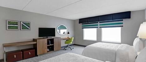 Habitación de hotel con dos camas, un escritorio, una silla, un televisor y una ventana con persianas.
