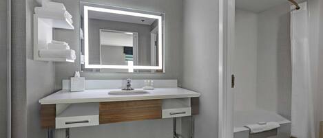 Een moderne badkamer met een witte wastafel, een grote spiegel, een douche en een handdoekrek.