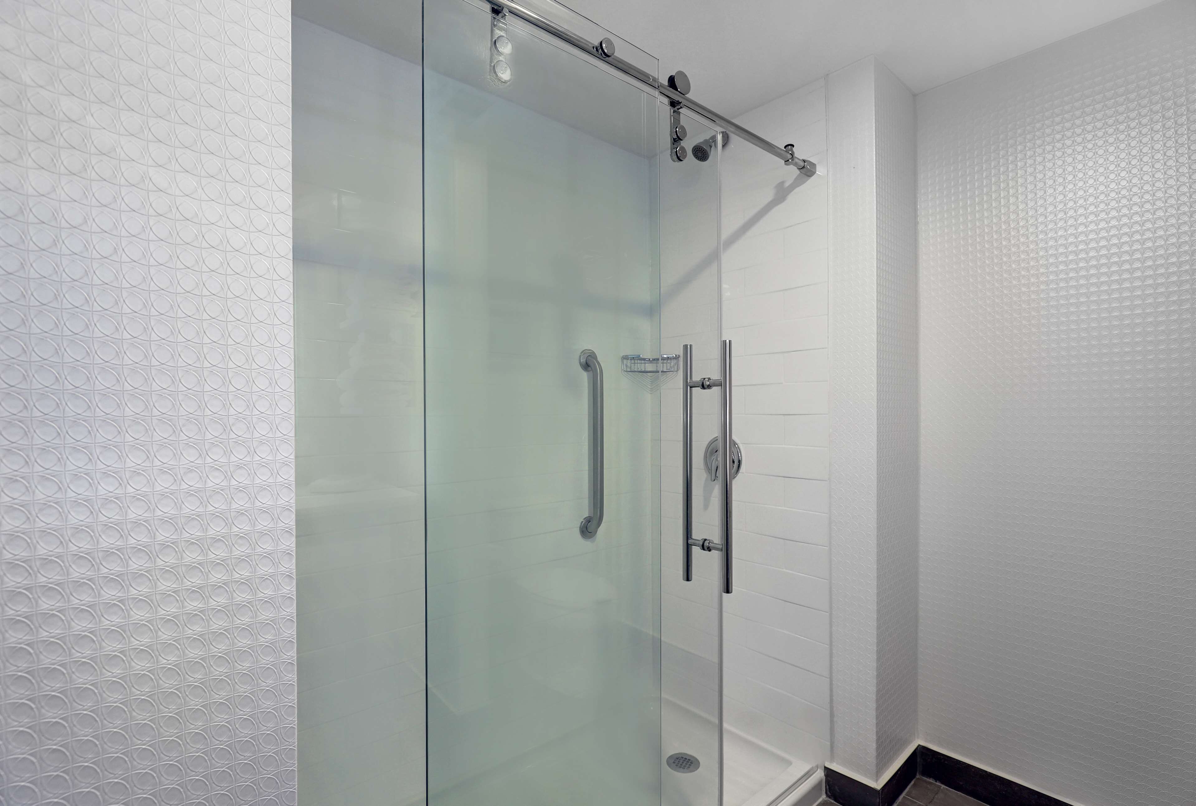 Une douche entièrementClose avec une paroi en verre, une barre d’appui et une porte en verre.