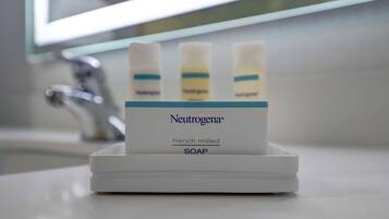 Saippua-annostelija, jossa on kolme Neutrogena®-merkittyä saippuaa ja valkoinen pohja.