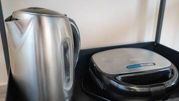 Uma chaleira de aço inoxidável e um dispositivo eletrônico preto compacto sobre uma bandeja preta.