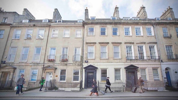 A row of traditional European townhouses with uniform facades, a central entrance, and a small balcony on the second floor. - The Georgian Loft Apartment Central Bath (Bath)