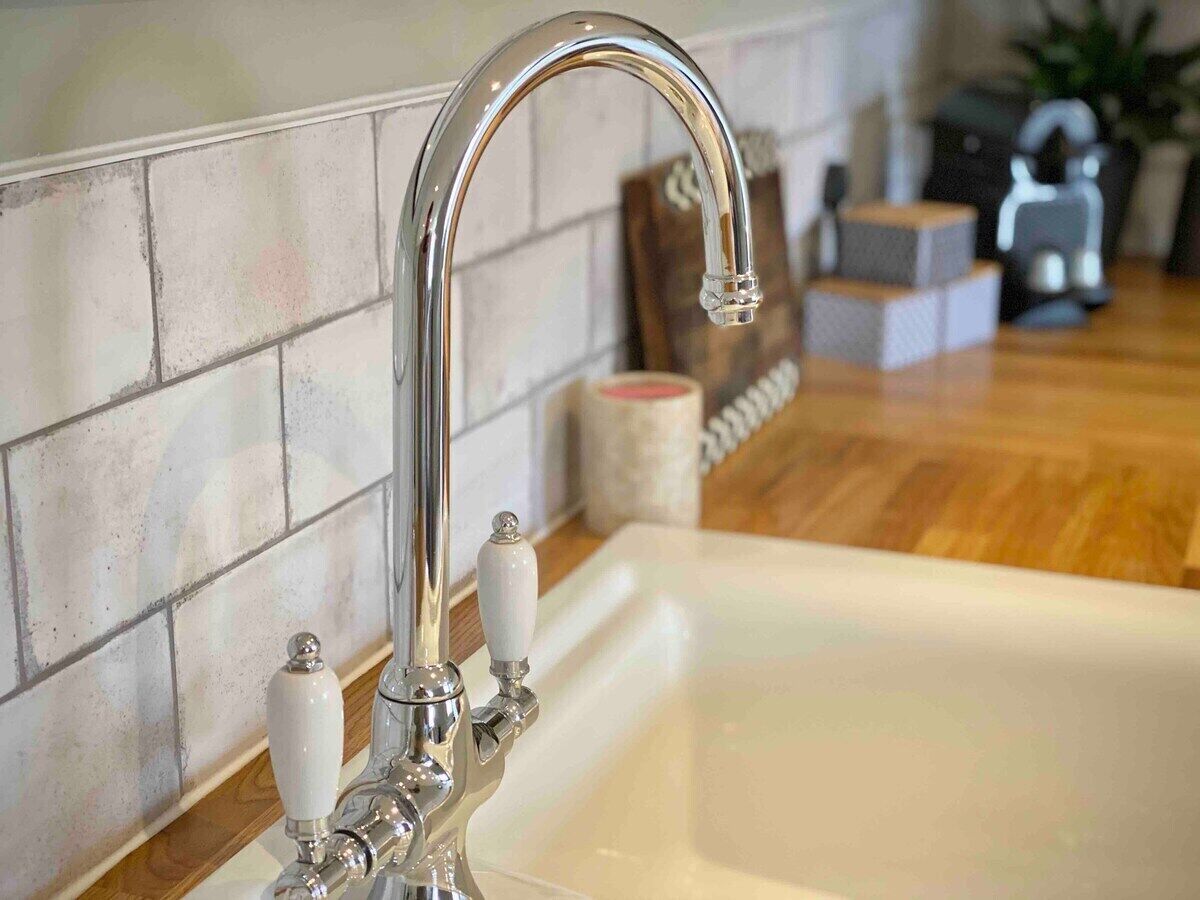 A modern bathroom with a chrome faucet, a white sink, and a tiled backsplash.